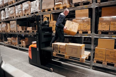 Operario descargando productos el almacén con un packaging adecuado a la logística del almacén